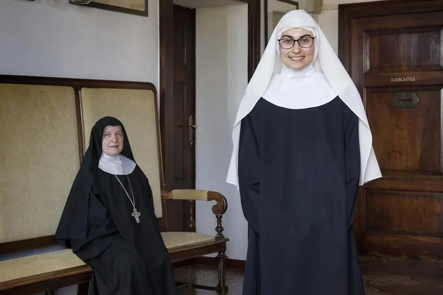 In the foreground, Sister Maria Bianca, 27 years old, one of the novices, recognizable by her white veil, and Mother Abbess Maria Grazia Girolimetto, 62