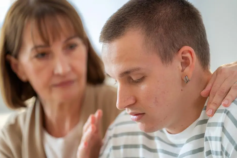 In a serious living room conversation, a teenage son argues while his concerned mother offers encouragement. This emotional family scene highlights communication challenges, love, support, and the parenting struggles of adolescence and understanding.