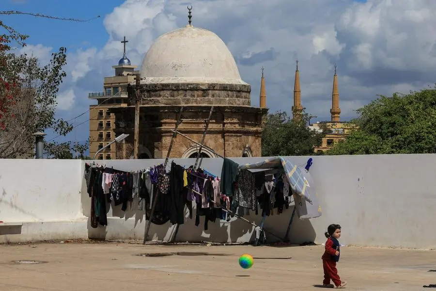 Beirut, un bambino in un rifugio per sfollati: sullo sfondo chiesa e moschea, mentre la guerra si intensifica. , REUTERS