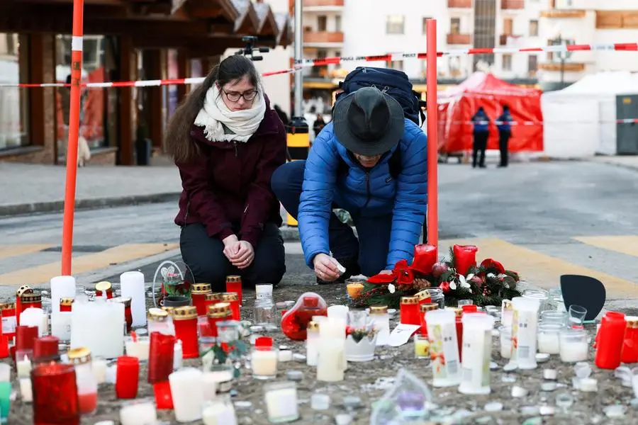 A man lights a candle next to the tributes laid for the victims on the ground outside the \"Le Constellation\" bar, after a fire and explosion during a New Year\\'s Eve party where several people died and others were injured, according to Swiss police, in the upscale ski resort of Crans-Montana in southwestern Switzerland, January 2, 2026. REUTERS/Stephanie Lecocq , REUTERS