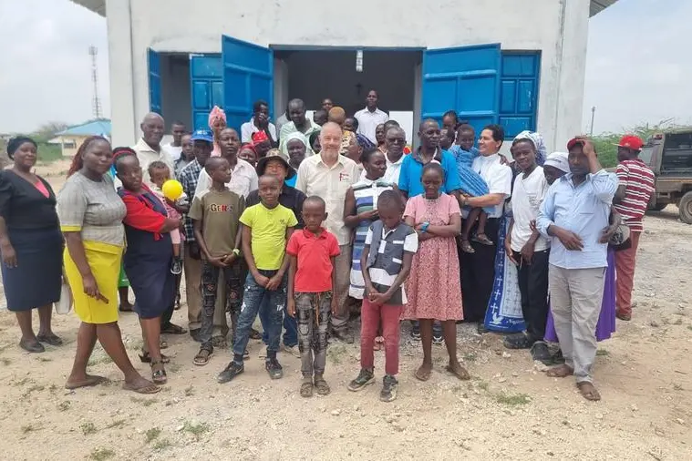Don Gigi Ginami davanti alla cappella a Bura Tana, in Kenya, con un gruppo d bambini e abitanti locali.