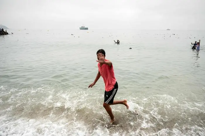 A migrant gestures as others swim through the waters close to the border barrier with Morocco to enter Spain's north Africa's Ceuta enclave on July 31, 2026. Thousands of migrants crossed overnight from Morocco into Ceuta enclave, a police source said, as Spanish Prime Minister was set to arrive to manage the latest migrant crisis on the border. In recent days, a total of around 40,000 migrants have crossed into the territory, population 80,000, the source added. (Photo by JORGE GUERRERO / AFP)