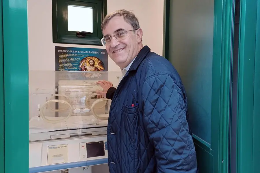 Don Antonio Ruccia in una foto del 2023 mentre indica la culla termica installata nella sua parrocchia di San Giovanni Battista nel quartiere Poggiofranco di Bari , ANSA