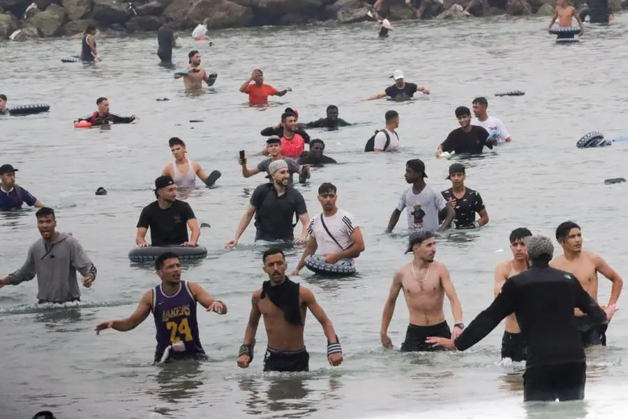 Un gruppo di migranti rimane sulla spiaggia vicino al valico di frontiera di Tarajal a Ceuta, in Spagna, 31 luglio 2026. Violenti scontri si sono verificati lungo il perimetro del confine mentre i migranti tentavano di entrare a Ceuta e Melilla dal Marocco.