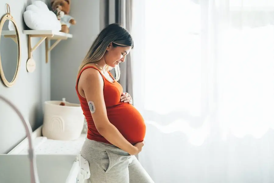Una donna in gravidanza accarezza il pancione nella serenit\\u00E0 della propria casa , Getty Images