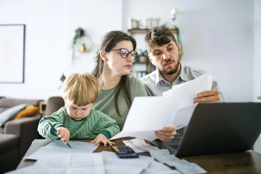 Una famiglia con un bambino piccolo alle prese con il bilancio domestico, tra bollette, tasse e spese mensili, in un periodo segnato dall’aumento del costo della vita