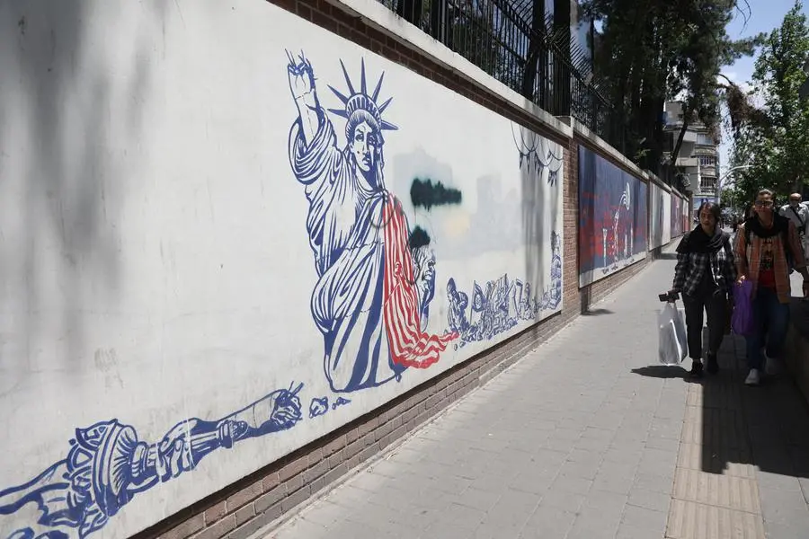 Persone camminano davanti a un murale anti-americano in una strada di Teheran, Iran , via REUTERS