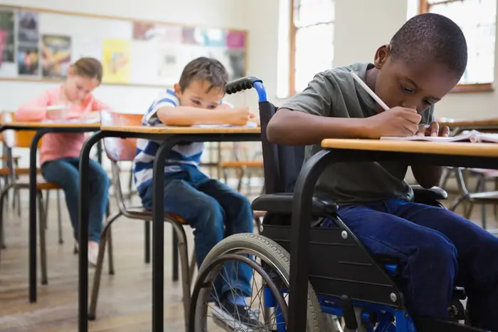 Cute pupils writing at desks in classroom at the elementary school