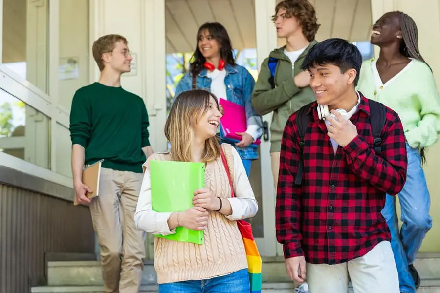 Happy Diverse Group of High School Students Exiting School Building on Steps , Getty Images