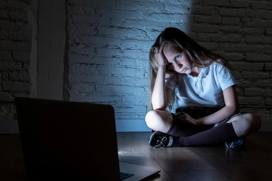 Scared sad girl bullied on line with laptop suffering cyberbullying and harassment feeling desperate and intimidated. Child victim of bullying stalker social media network , Getty Images/iStockphoto