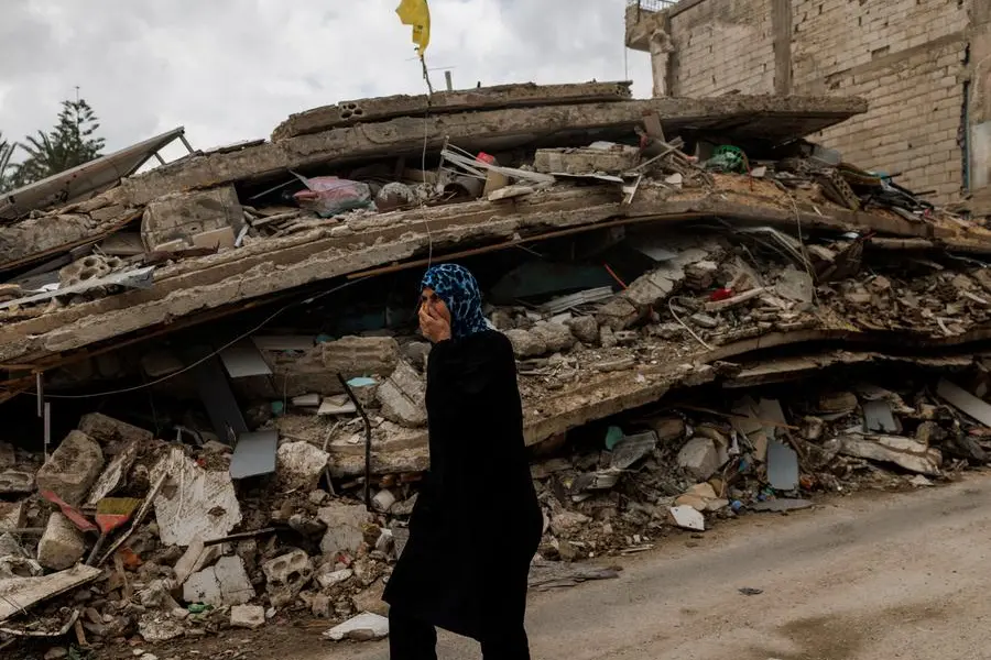 Una donna a Zrarieh, in Libano, cammina coprendosi il naso per proteggersi dall\\u2019odore proveniente da un edificio con abitazioni e un ristorante colpito da un attacco israeliano poche ore prima del cessate il fuoco, durante una tregua di 10 giorni tra Libano e Israele , REUTERS