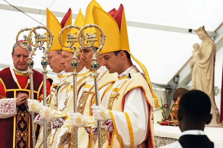 I quattro nuovi vescovi lefebvriani, da sinistra Pascal Schreiber, Michael Goldade, Michel Poinsinet de Sivry e Marc Hanappier, al termine della cerimonia di consacrazione episcopale celebrata a \\u00C9c\\u00F4ne, in Svizzera, il 1\\u00B0 luglio 2026. Con mitra e pastorale, pregano nella tensostruttura allestita all\\'esterno del seminario della Fraternit\\u00E0 Sacerdotale San Pio X. , AP /LAPRESSE